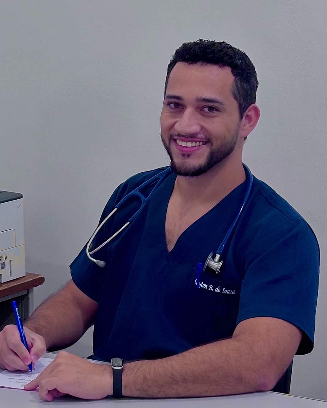 Dr. Cleyton no consultório, sorrindo enquanto faz anotações